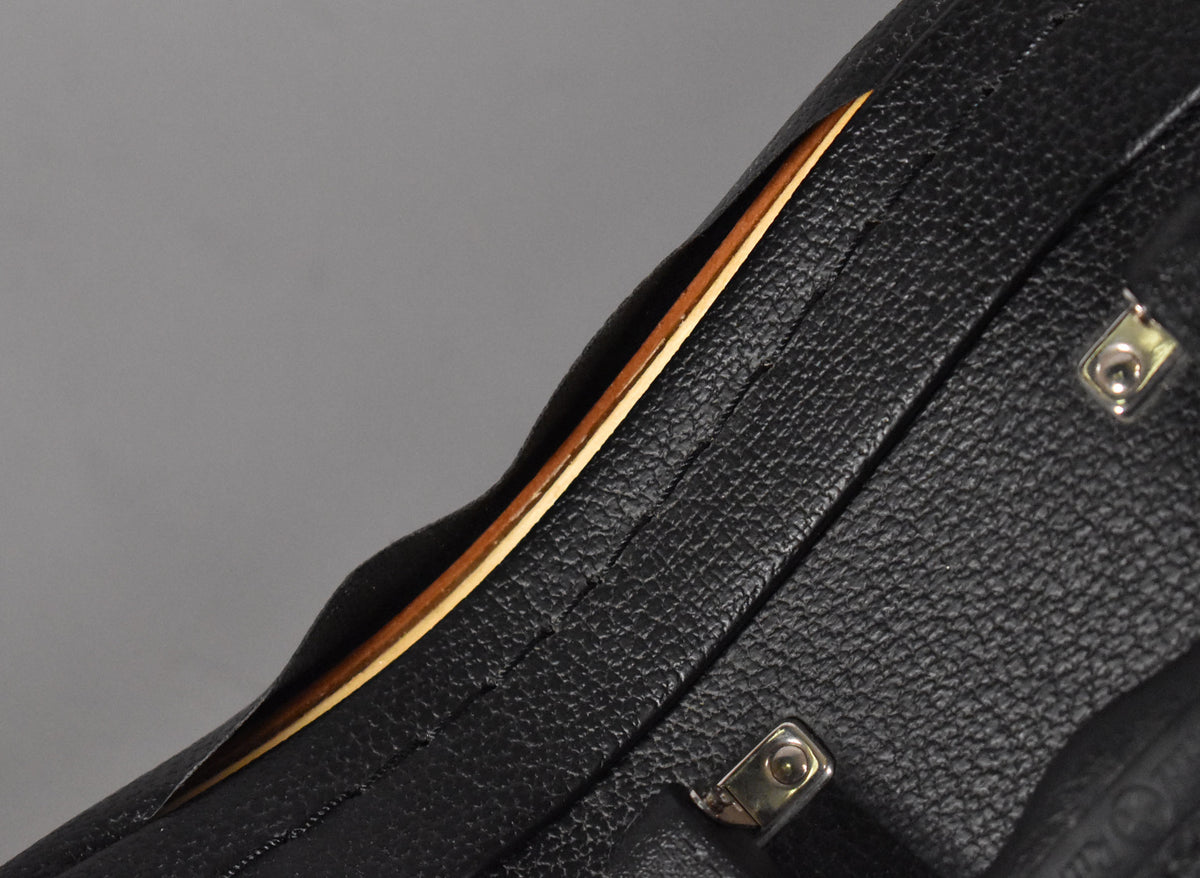 Close-up of the black textured hard case, showing a gap where the lid meets the body, revealing a light brown interior trim.