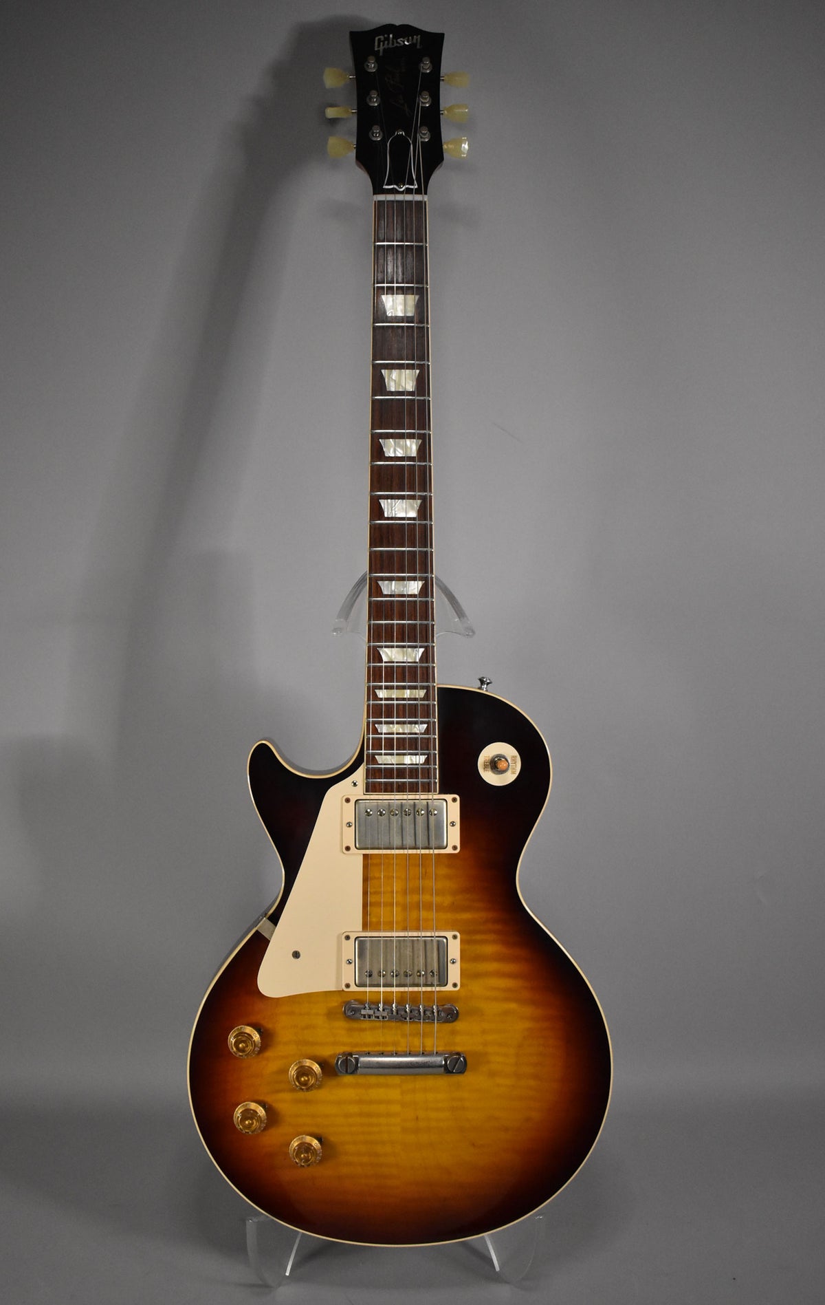 Full view of a Gibson Les Paul electric guitar with a sunburst finish, cream pickguard, and trapezoid inlays.