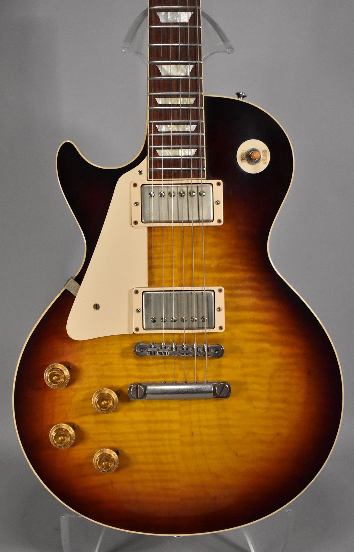 The left-handed Les Paul's body and neck are framed, showing a faded tobacco burst finish with prominent flame maple figuring.