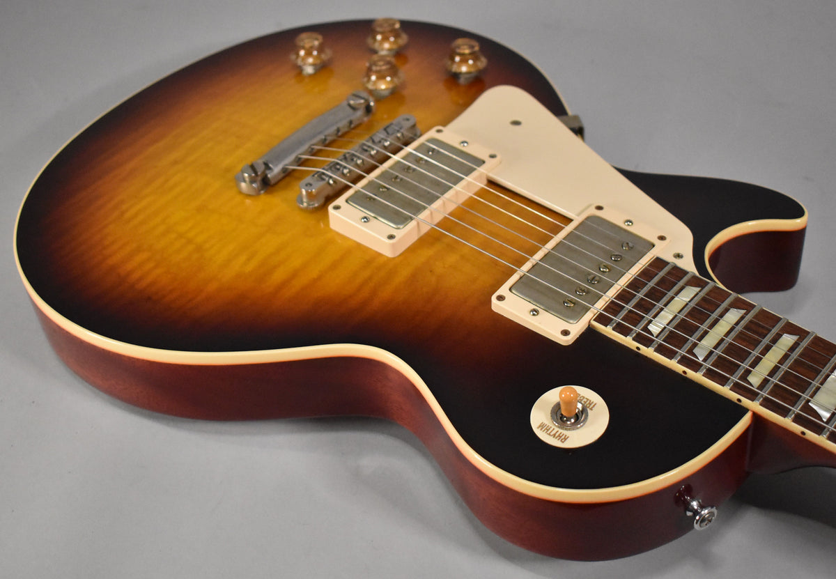 Left-handed Les Paul with a faded tobacco burst finish, cream binding, two humbuckers, and a "Rhythm" labeled toggle switch.