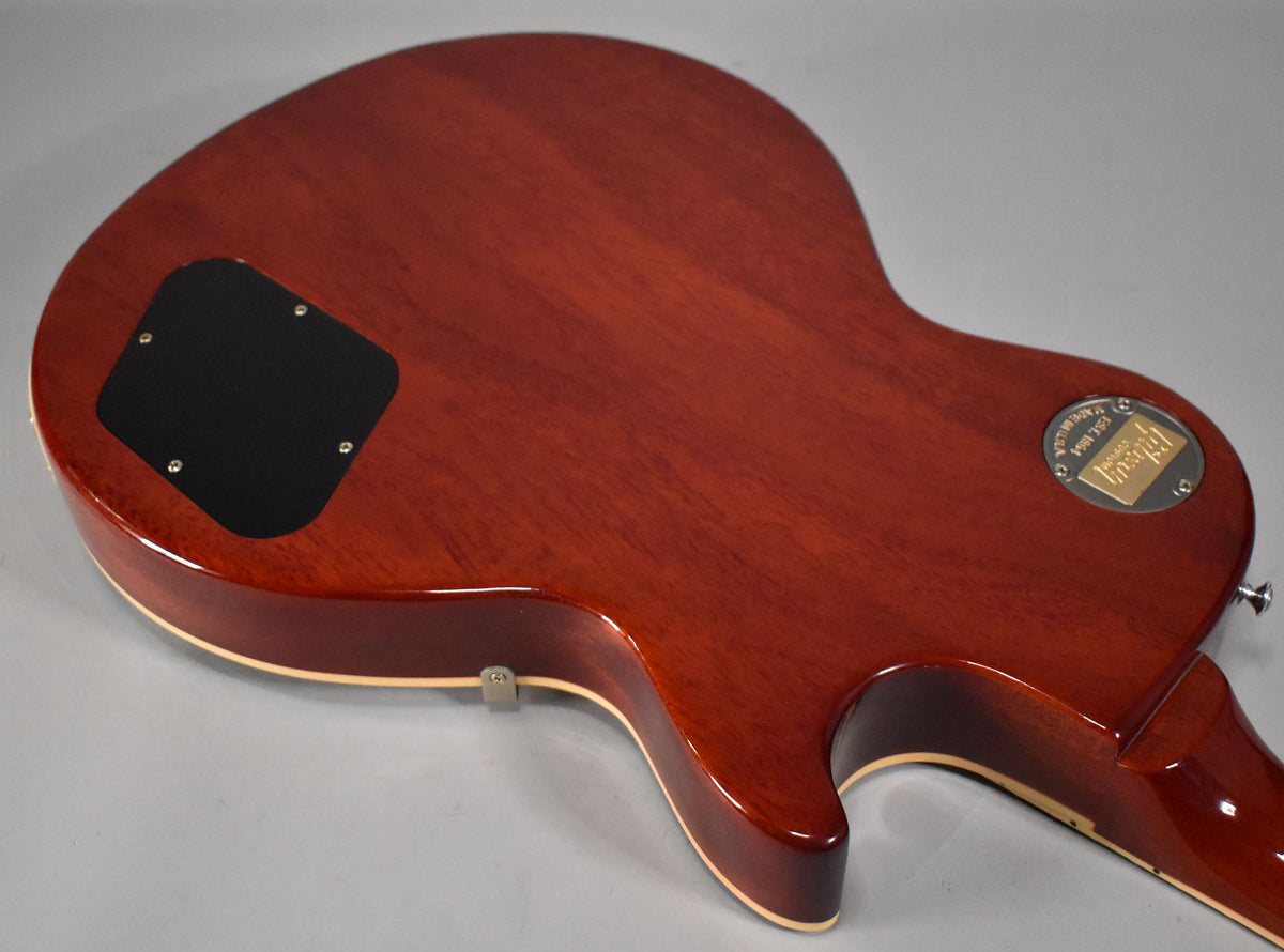 The guitar's faded tobacco back, with a black control cavity cover and a gold medallion, shows light wear near the neck joint.
