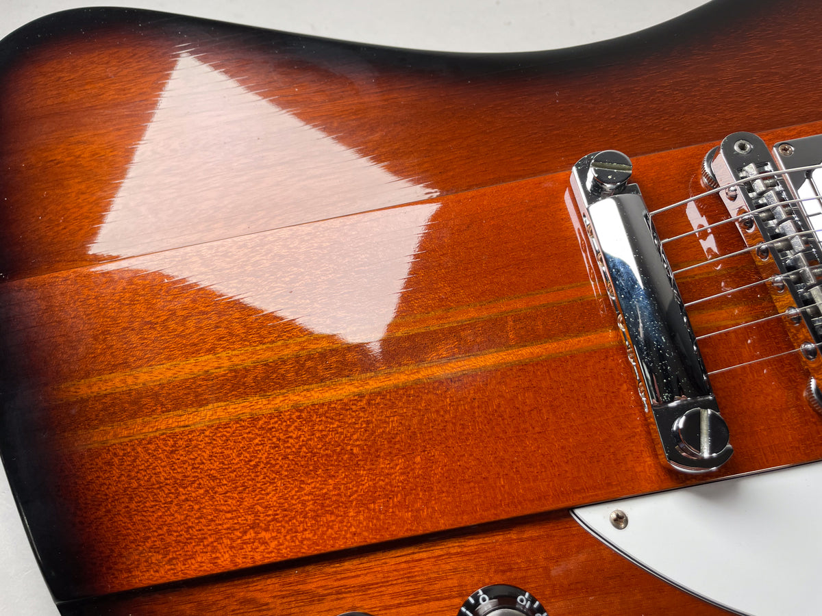 Close-up of the guitar's glossy sunburst body, showing a chrome tune-o-matic bridge and part of a white pickguard.