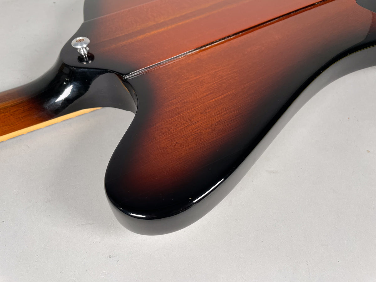 The guitar's sunburst body, with a strap button on the upper horn, transitions from dark brown to black at the edges.
