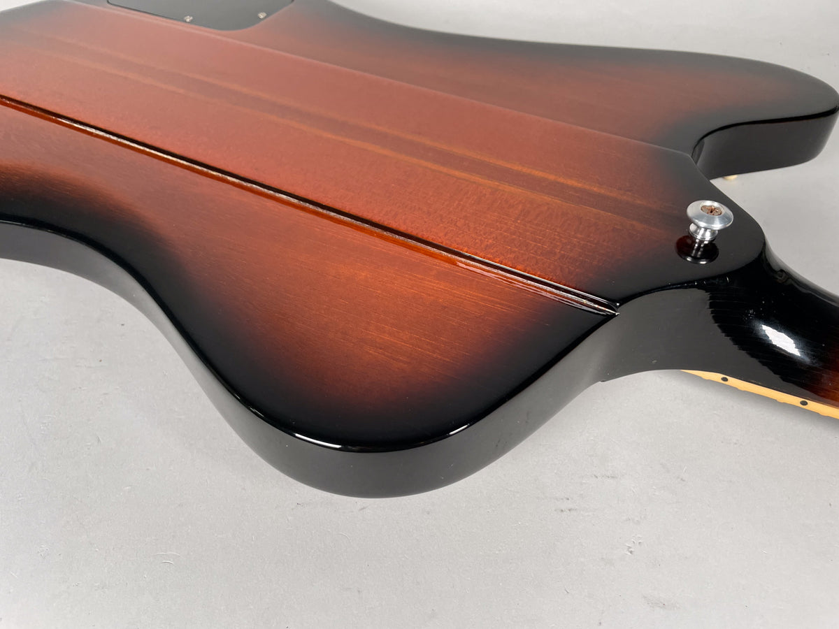 The guitar's sunburst finish body and neck joint are shown from the back, with a chrome strap button visible.