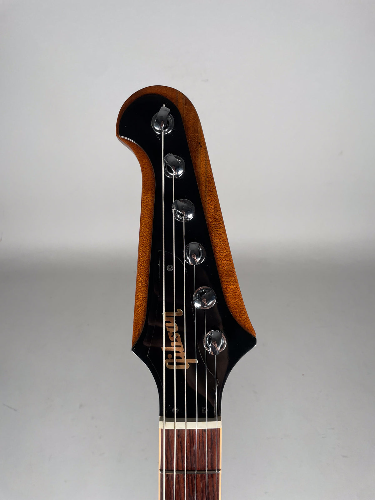 The guitar's headstock is framed, showing a black face with six chrome tuners and a dark wood back, with light wear.