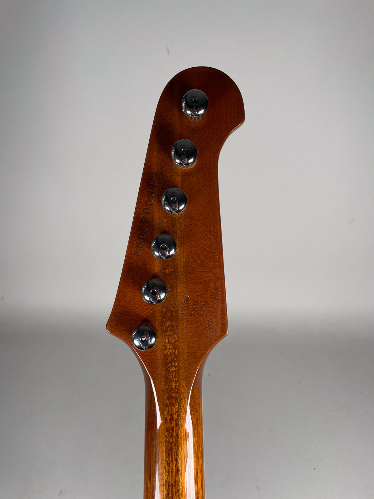 Rear view of the Firebird's headstock and upper neck, showing a glossy sunburst finish, six chrome tuners, and light wear.