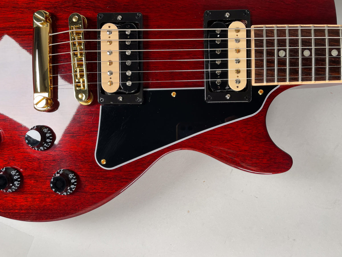 Close-up of the cherry finish body, showing gold hardware, two cream-bobbin humbuckers, a black pickguard, and four black control knobs.