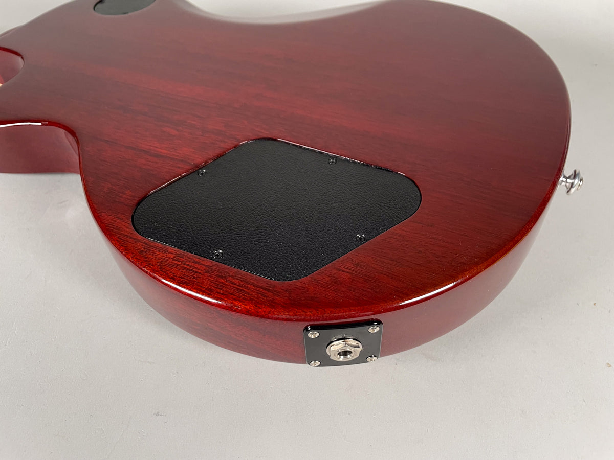 The back of the cherry red guitar shows a black control cavity cover and a chrome output jack on the lower bout.
