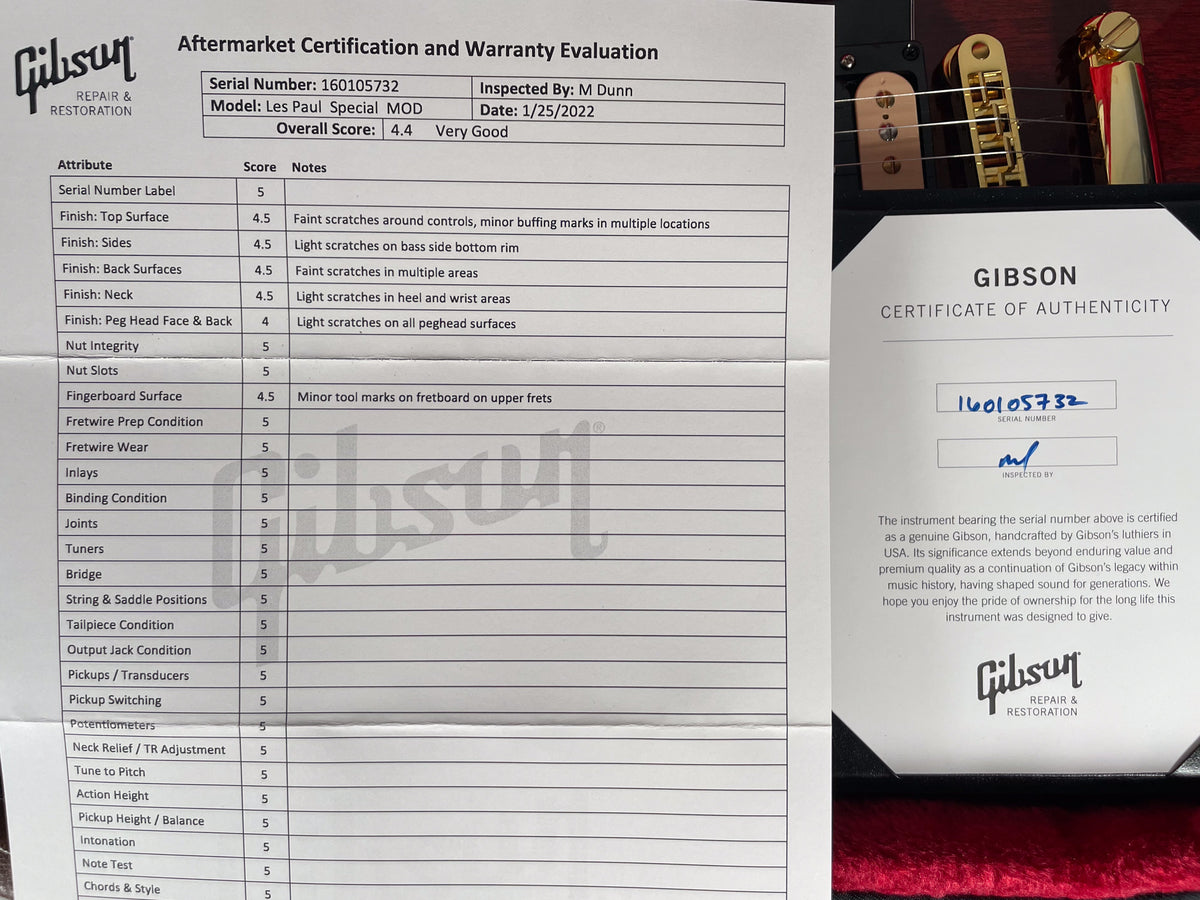 Close-up of a Gibson Certificate of Authenticity and a repair evaluation form, with the guitar's gold hardware visible at the top right.
