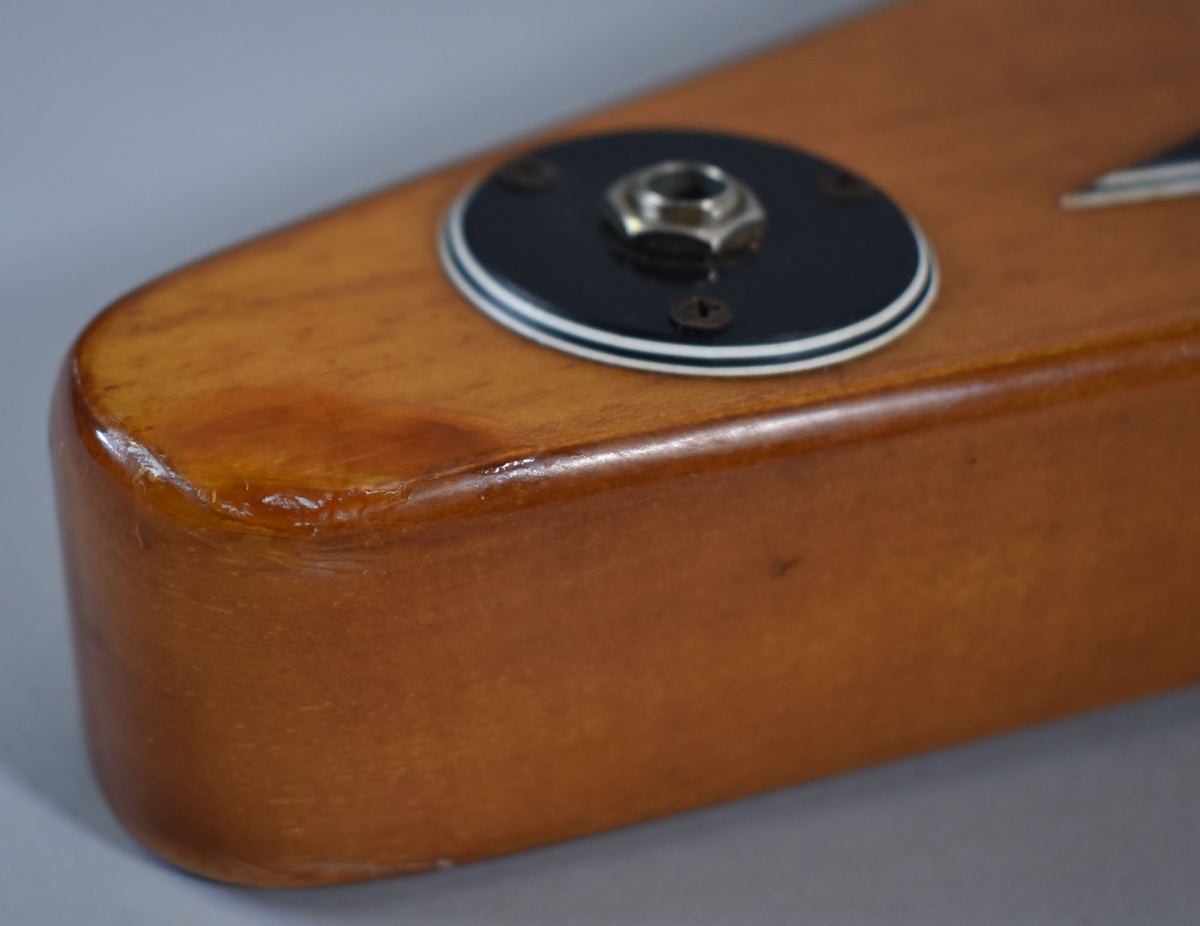 Close-up of the natural finish body's lower bout, showing the black and white output jack plate and minor finish wear on the edge.