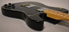Black Telecaster Deluxe, angled from the lower bout, showing four black numbered control knobs, two chrome humbuckers, and a maple neck.