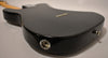 The black guitar's body is angled from the back, showing the input jack, strap button, and string-through-body ferrules.
