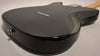 The black Telecaster body is angled, showing the shiny back with six string ferrules and a chrome output jack on the lower bout.
