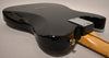 The black Telecaster's glossy back body, with string-through ferrules and neck plate, shows minor scuffs and a small ding on the lower bout.