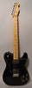 Full-length view of a glossy black Telecaster with a maple neck, two humbuckers, and four chrome control knobs on a white pickguard.