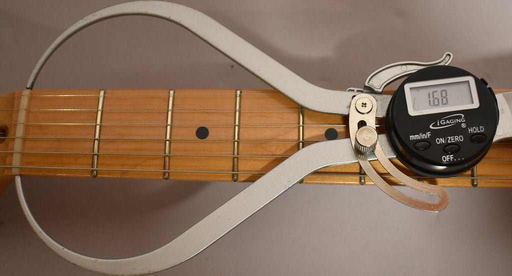 A digital caliper measures the maple fretboard and frets, showing a reading of 1.68.