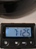 A close-up of a digital scale displaying "7:12.5" in blue, with power, M, MODE, and T buttons below.