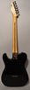 The back of a glossy black Telecaster, showing a light wood neck, chrome tuners, and six string ferrules on the body.