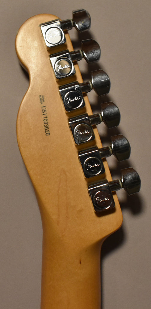 Close-up of the guitar's natural wood headstock and neck, showing six chrome tuning machines with light wear and a serial number.