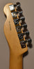 Close-up of the guitar's natural wood headstock and neck, showing six chrome tuning machines with light wear and a serial number.