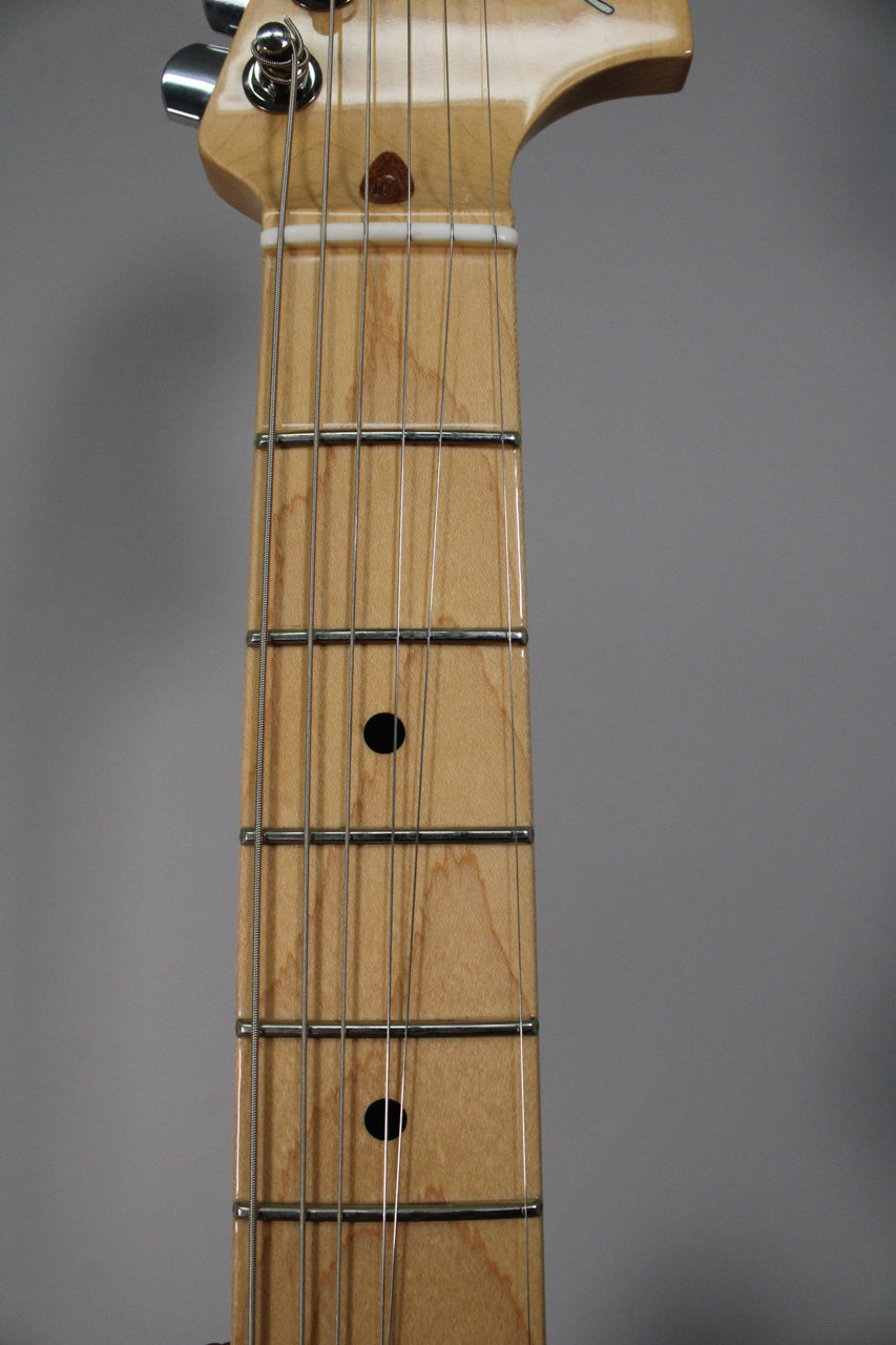Close-up of the maple fretboard and headstock, showing the nut, first five frets with black dot inlays, and tuning pegs.