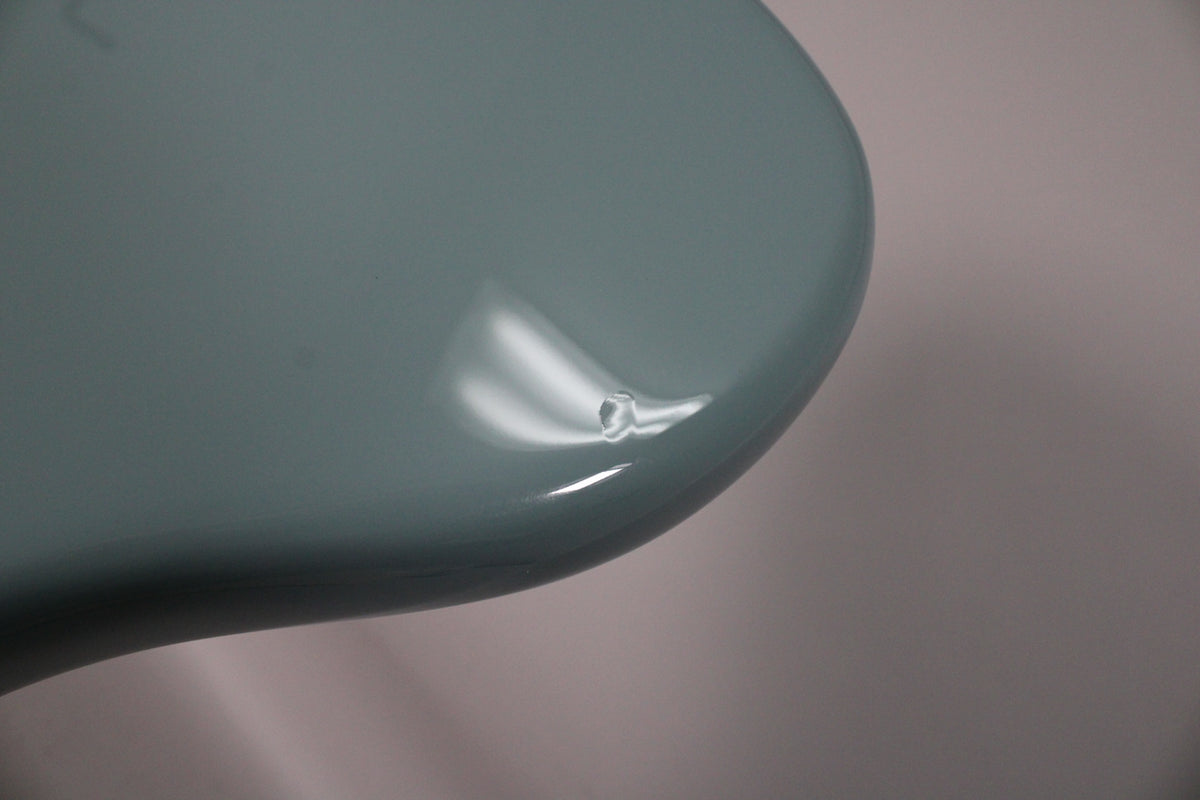 Close-up of the Sonic Grey guitar body's lower bout, showing a small chip in the glossy finish near the edge.