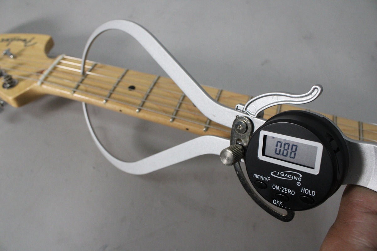Close-up of the guitar's maple fretboard with a digital caliper measuring fret height at 0.88mm, showing light wear on the frets.