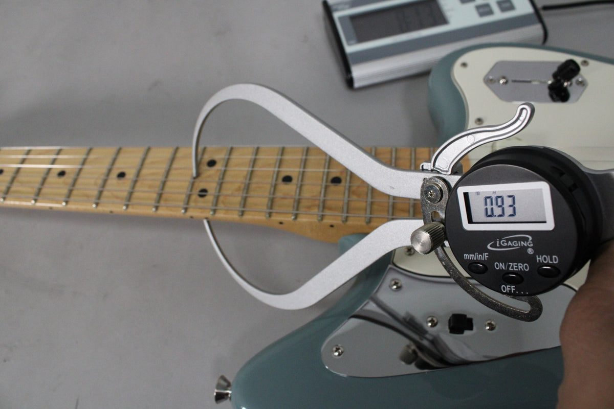 A digital caliper measures the fret height on the maple fretboard of the Sonic Grey Jaguar.