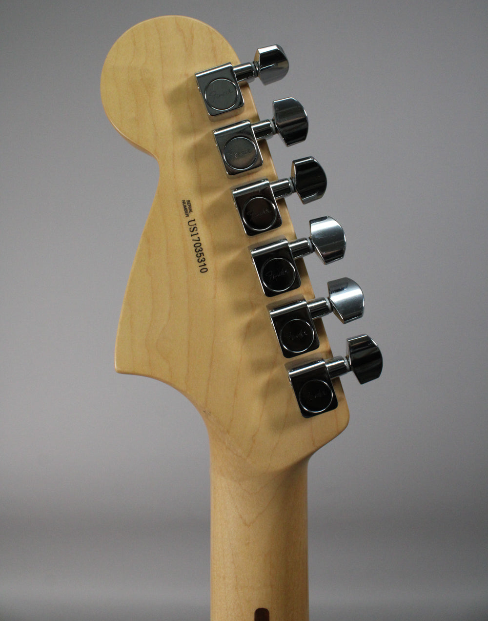 Rear view of the natural finish headstock and neck, showing six chrome tuners and a serial number on the back of the headstock.