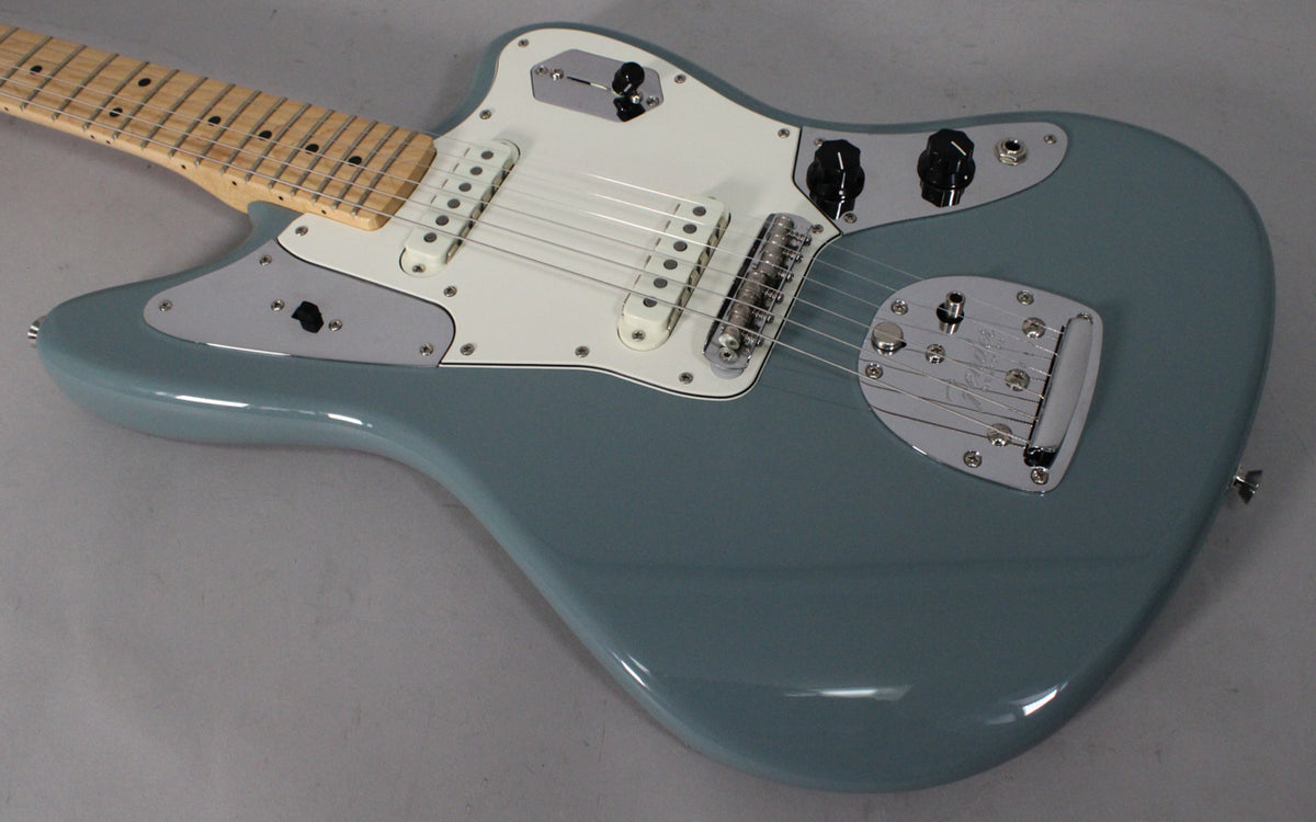 The Sonic Grey Jaguar's body, white pickguard, chrome control plates, and vibrato system are visible from a high angle.
