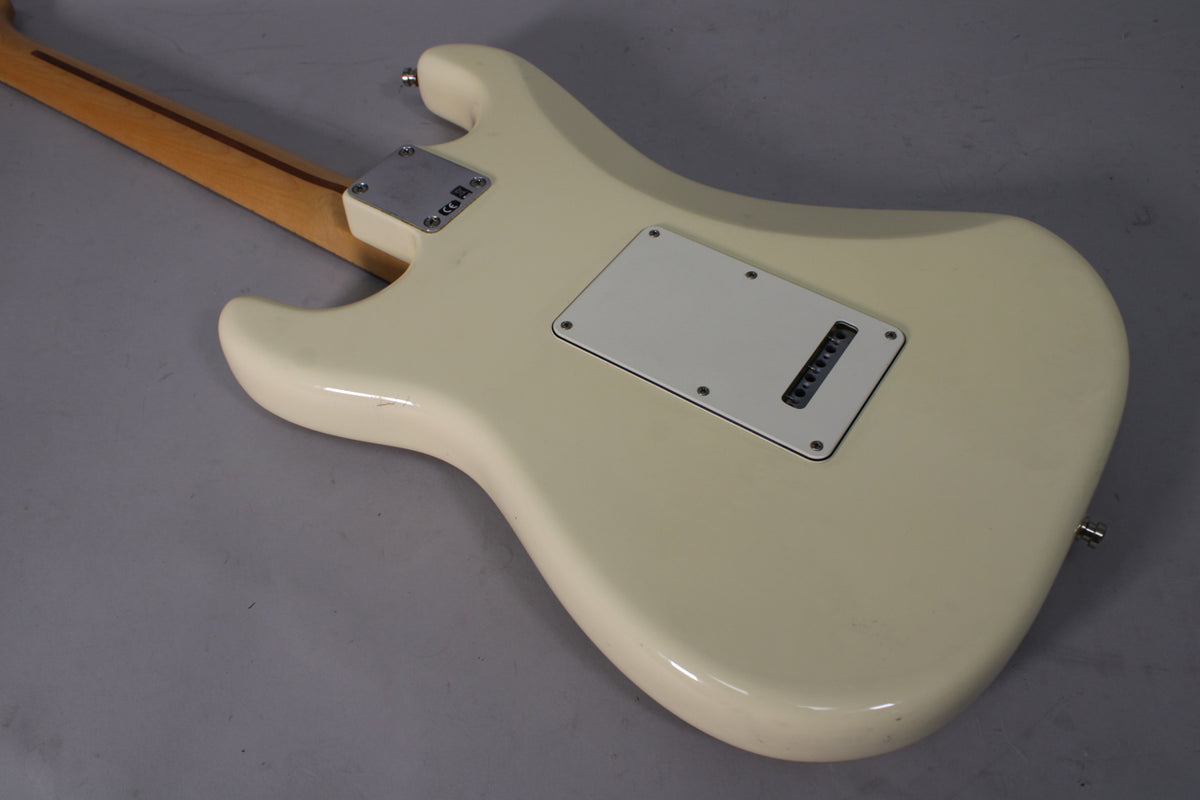 The back of an Olympic White Stratocaster body with a white tremolo cover, showing light wear and a few small dings.