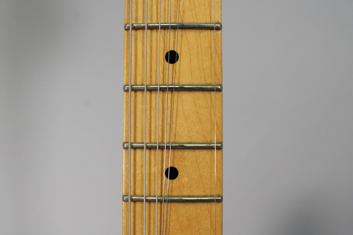Close-up of the maple fretboard, showing five frets with two black dot inlays and light wear on the frets and wood.