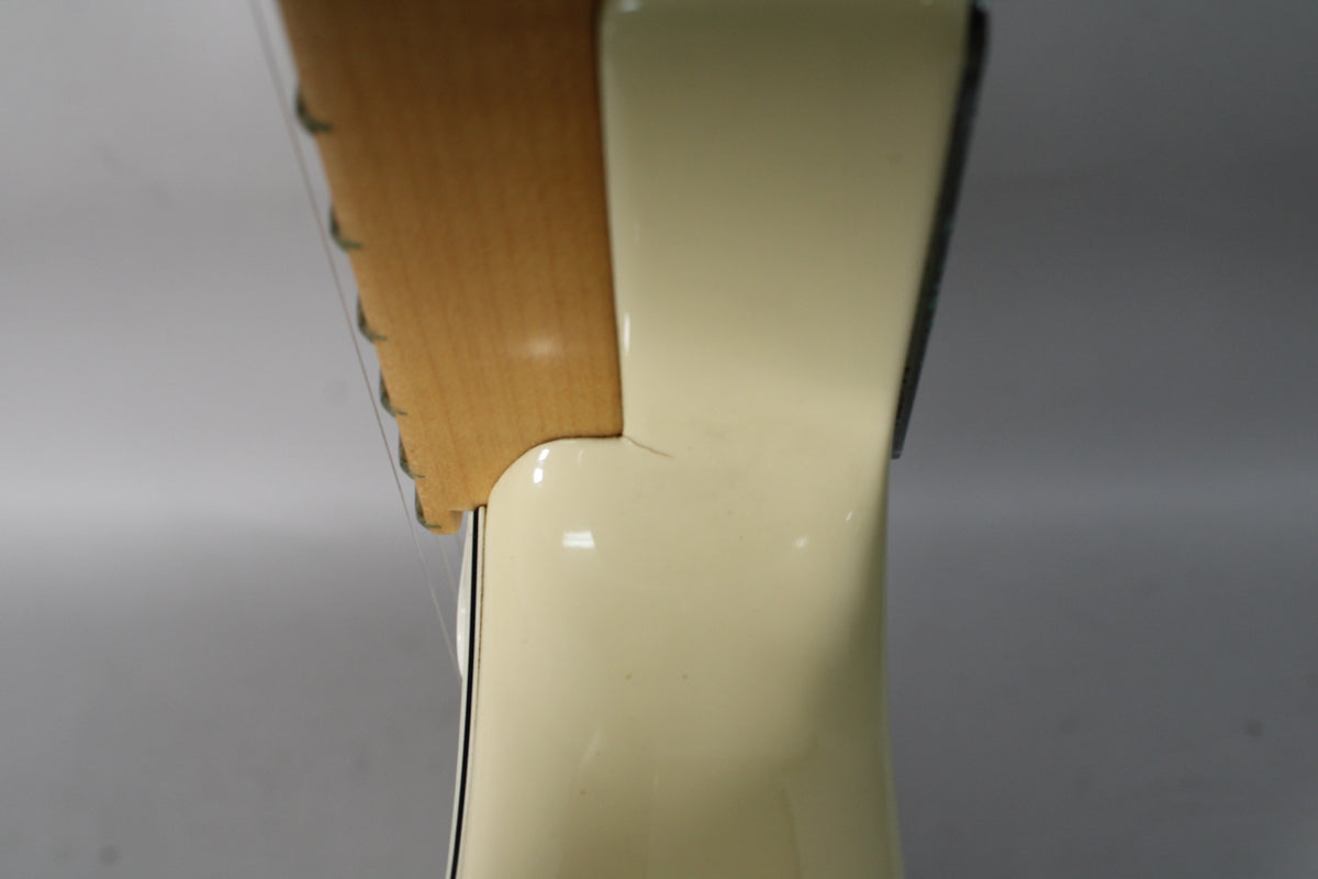 Close-up of the Olympic White guitar's neck joint from above, showing a small finish crack where the neck meets the body.
