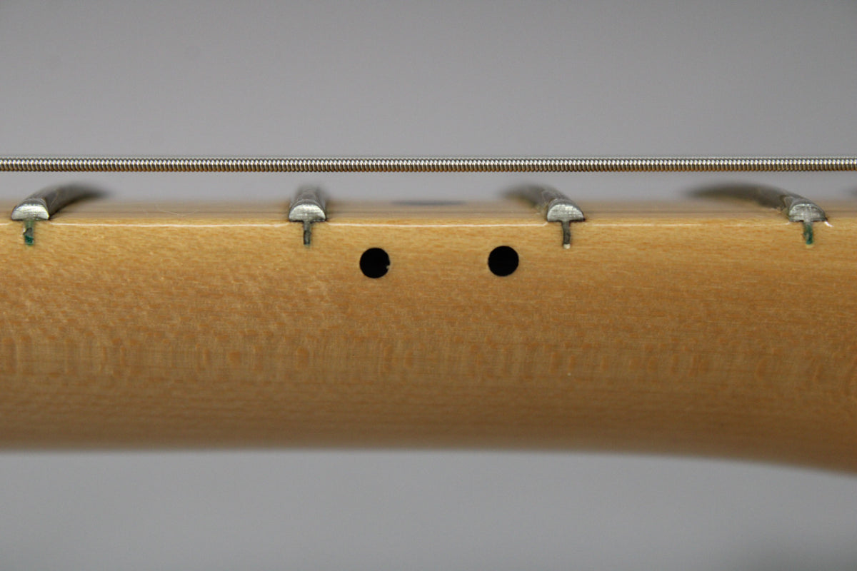 Close-up of the maple fretboard, showing two black dot inlays between the 2nd and 3rd frets, and a single wound string.