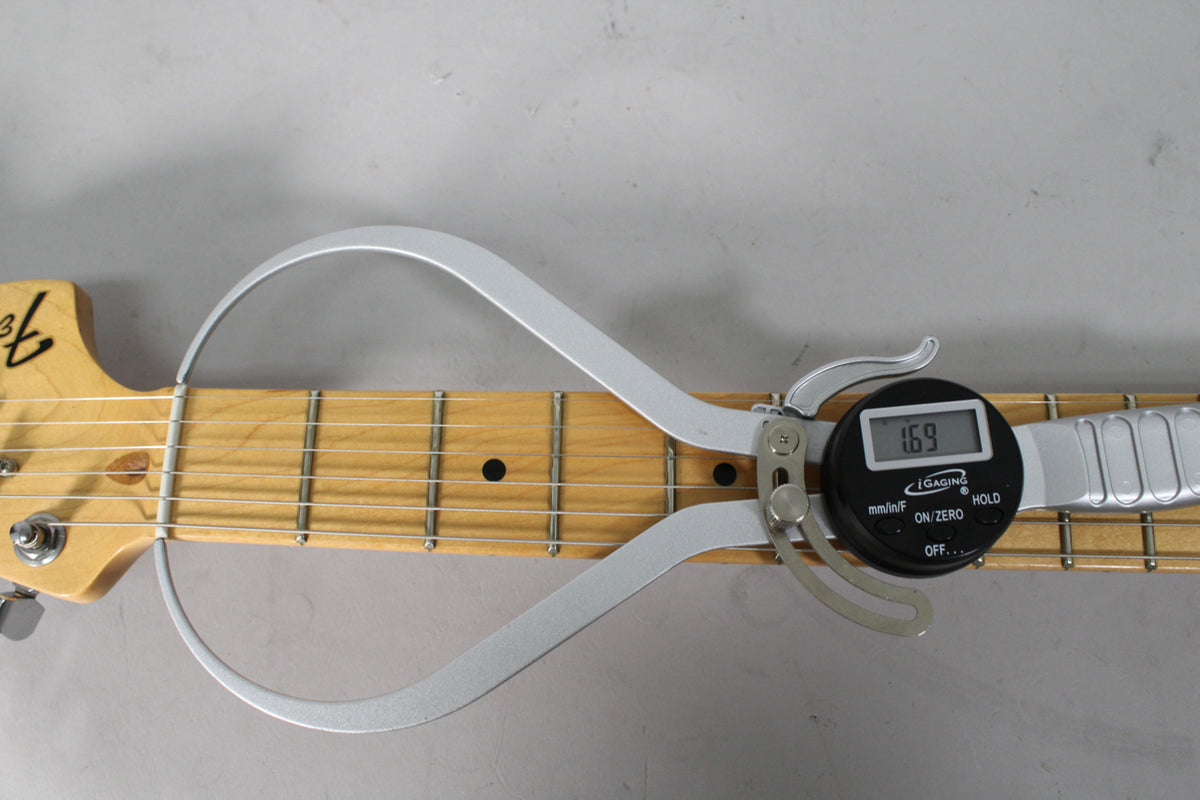 A digital fret height gauge measures 1.69mm on the maple fretboard of a Stratocaster, showing light wear on the frets.