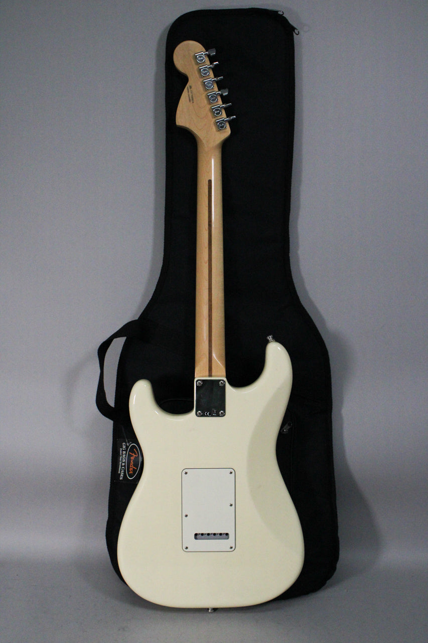 The back of an Olympic White Stratocaster with a maple neck and chrome tuners, resting against a black gig bag.
