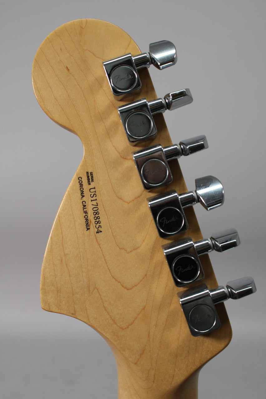 The back of a light maple headstock with six chrome tuners, angled from the left, showing a serial number.