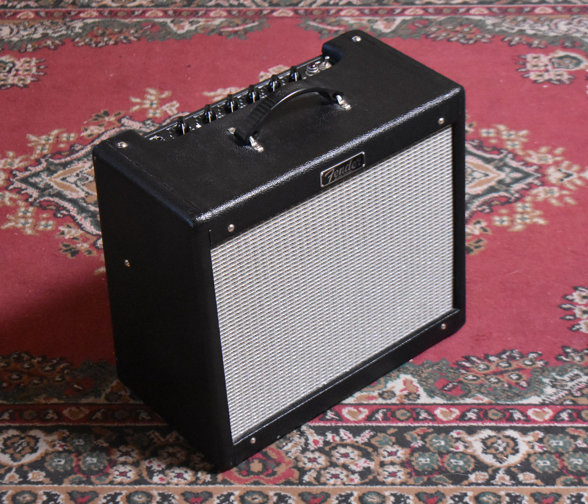 Black combo amplifier with a silver grille, viewed from above and to the right, showing the top handle and control panel.