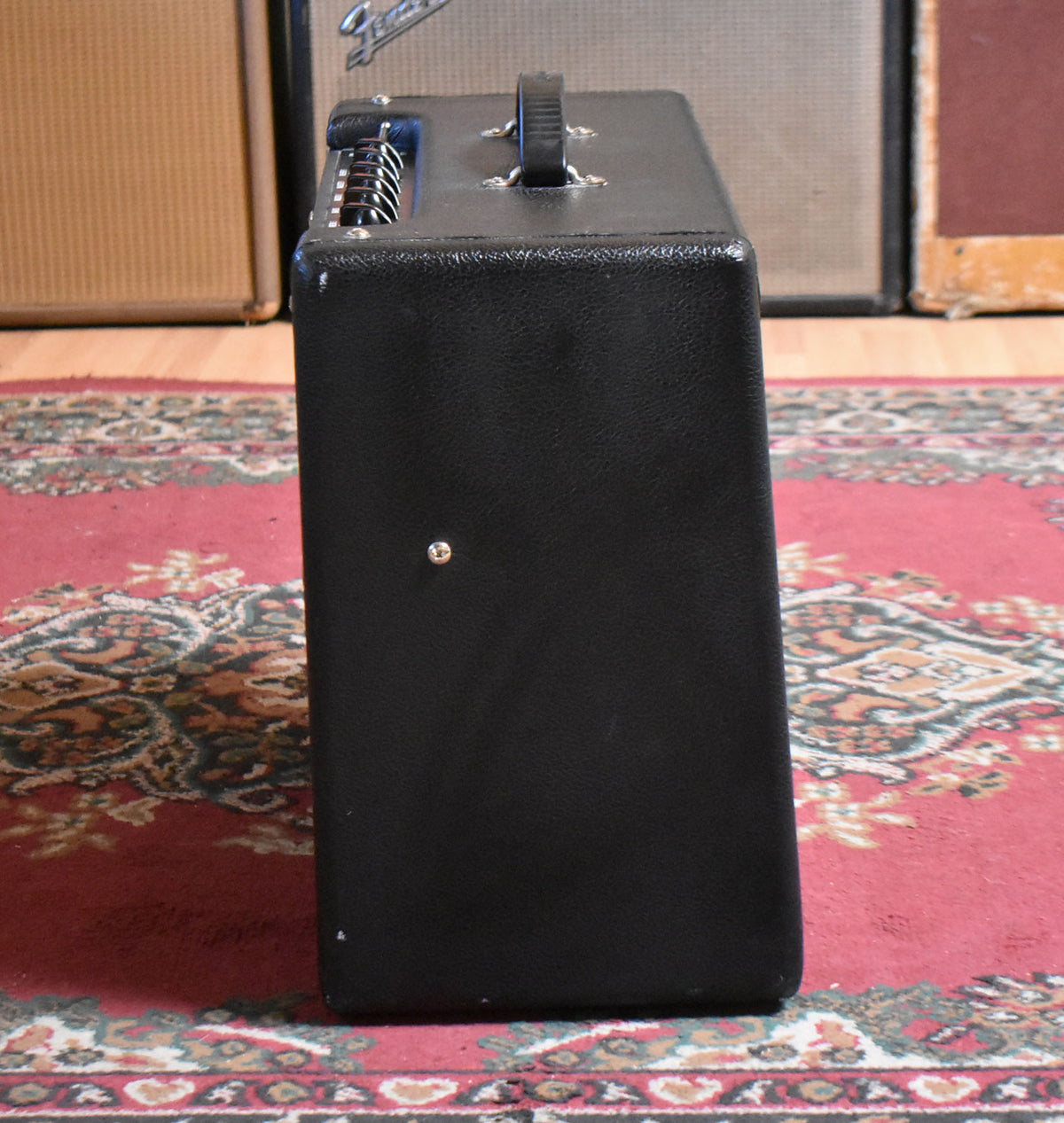 Black combo amp, viewed from the right side, showing the textured Tolex finish, top handle, and control panel with silver knobs.