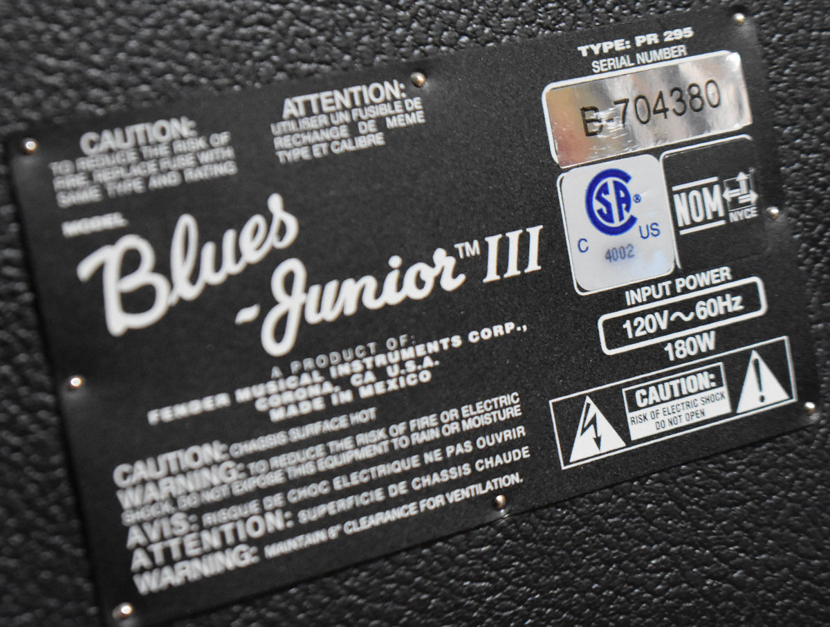 Close-up of the amplifier's black rear label, showing the serial number E-704380 and electrical warnings, with minor scuffs.