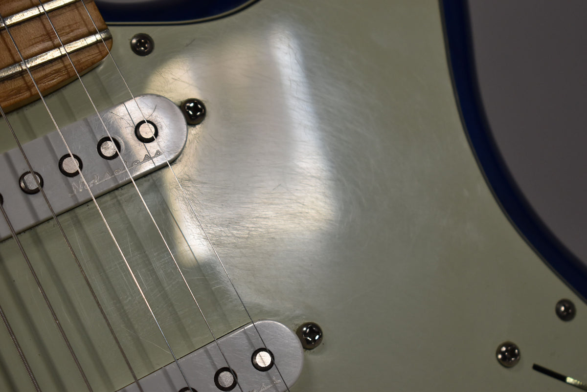 Close-up of the guitar's light green pickguard, showing light scratches and two silver single-coil pickups with visible pole pieces.