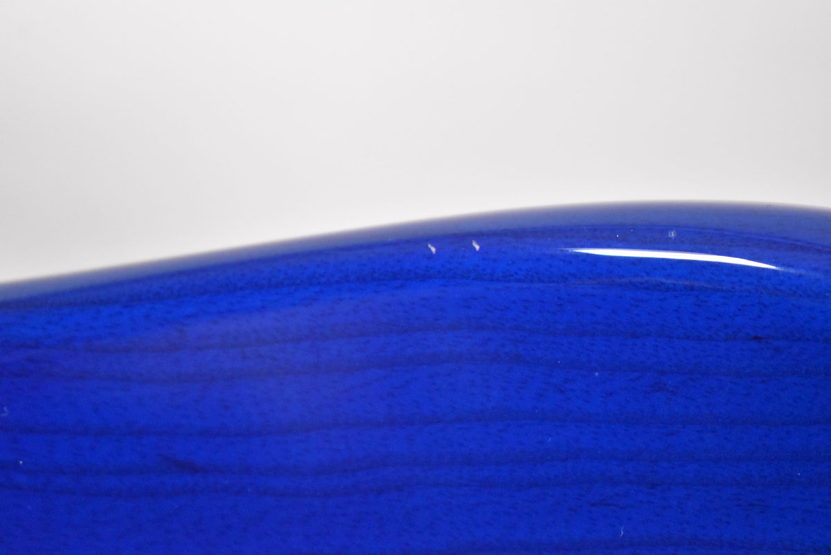 Close-up of the guitar's sapphire blue body, showing two small white chips in the finish along the upper curve.