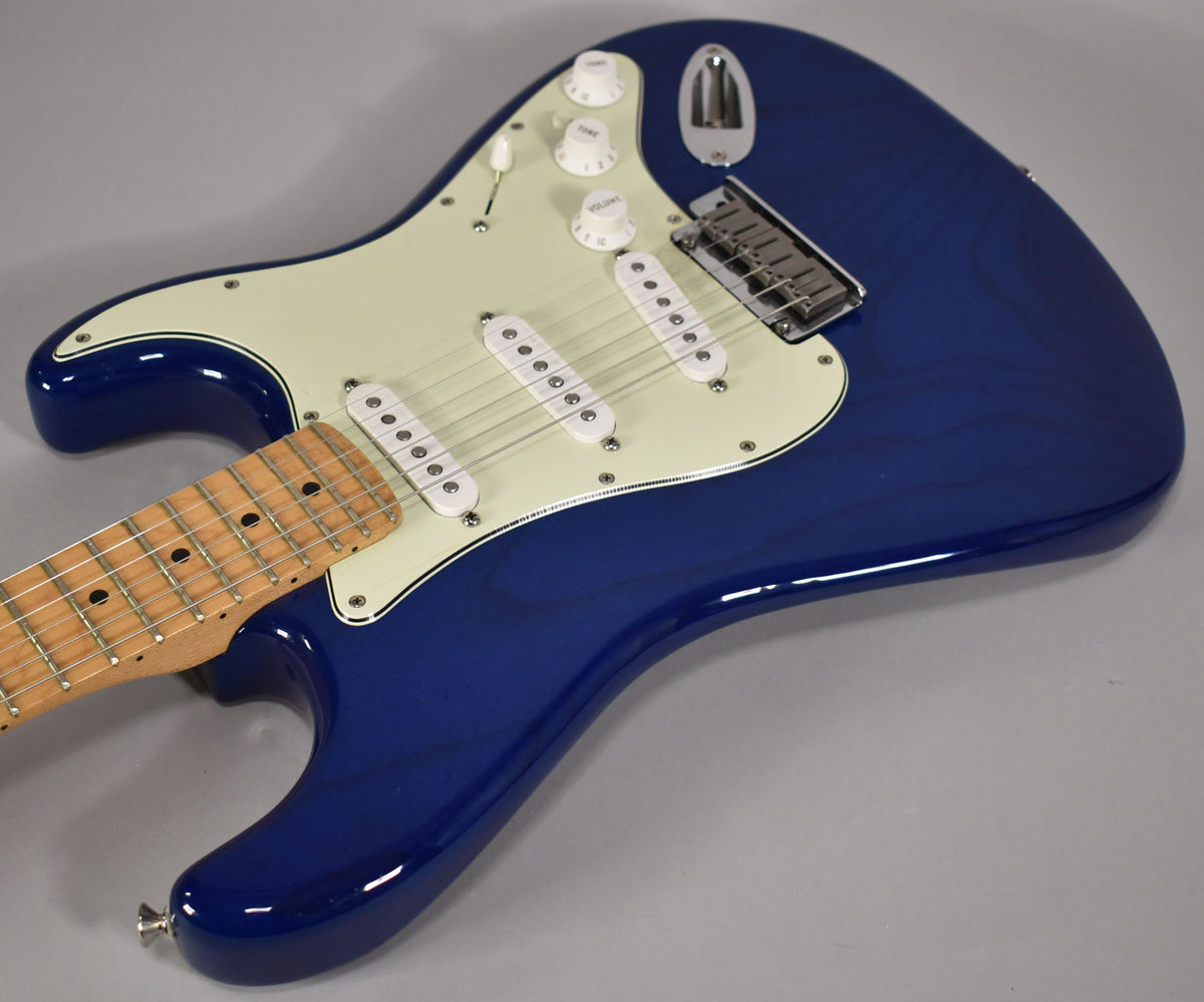 Upper body of a sapphire blue Stratocaster with a maple fretboard, cream pickguard, three single-coil pickups, and chrome hardware.
