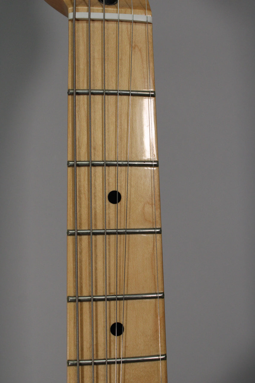 Close-up of the maple fretboard, showing the nut, frets, strings, and two black dot inlays on a glossy finish.