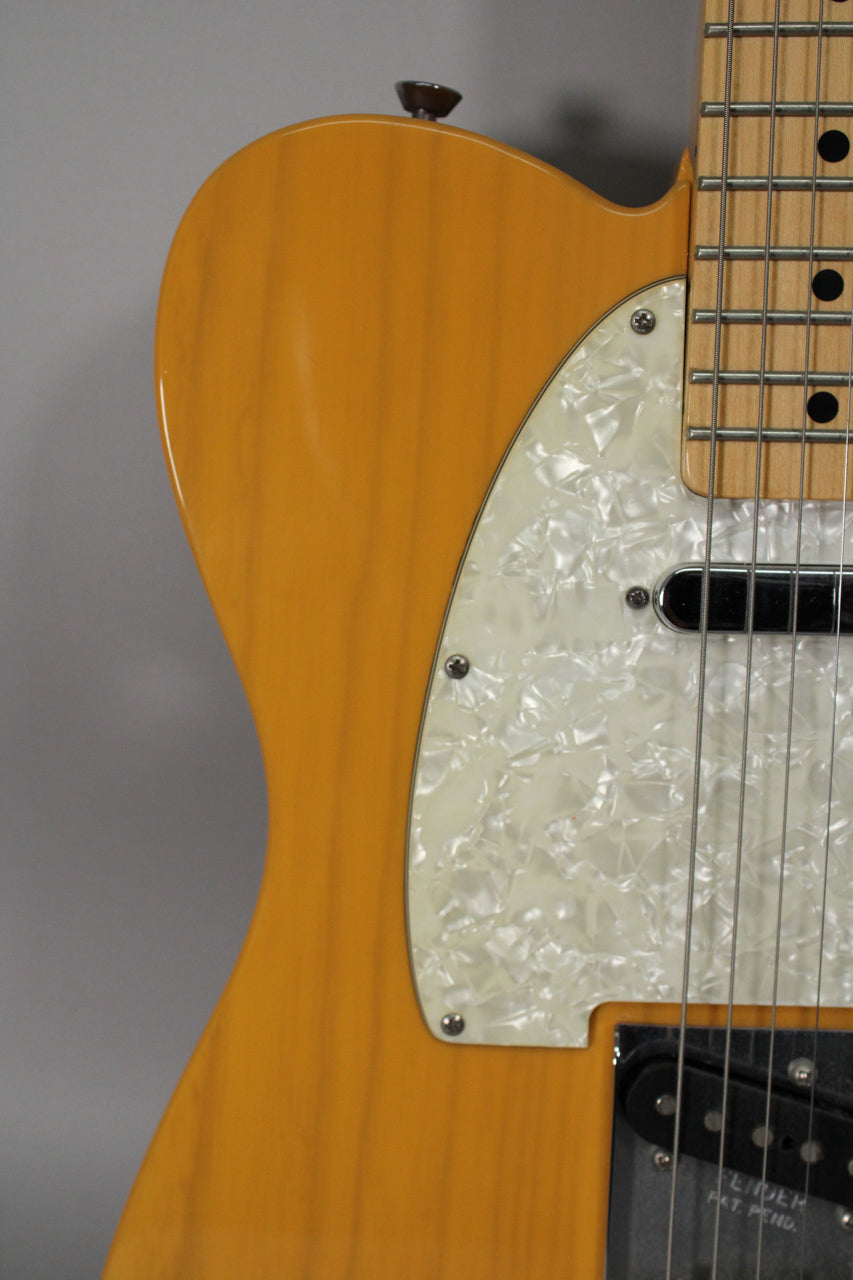Close-up of a butterscotch blonde Telecaster body with a pearloid pickguard, showing the neck pickup and maple fretboard.