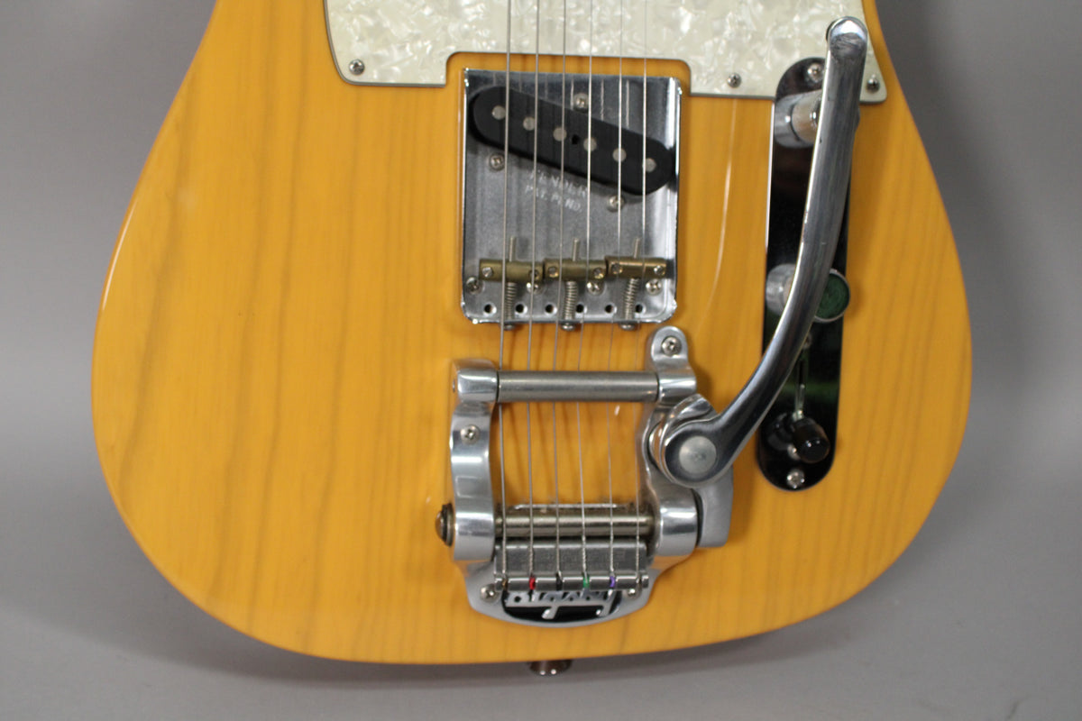 Close-up of the Telecaster's butterscotch blonde body, showing the Bigsby vibrato, bridge pickup, and pearloid pickguard.