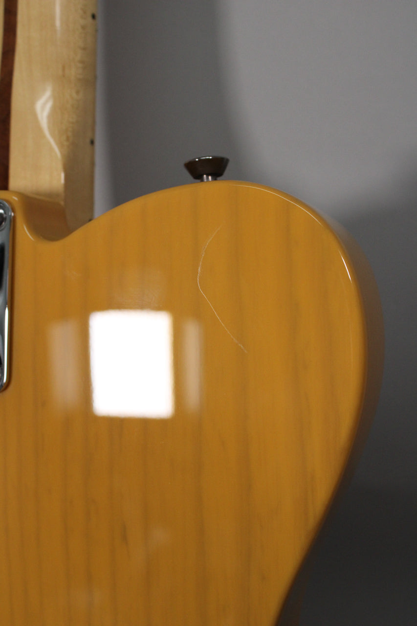 Close-up of the guitar's butterscotch blonde body with a visible scratch, showing the wood grain and a dark brown strap button.