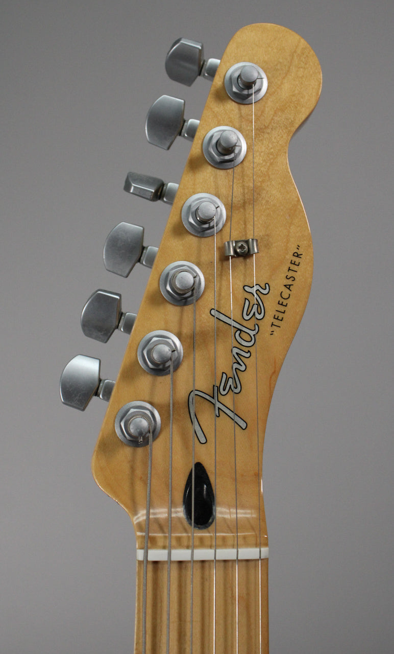 Close-up of the guitar's headstock, showing six satin-finish tuners, a string tree, and the light wood grain of the neck.