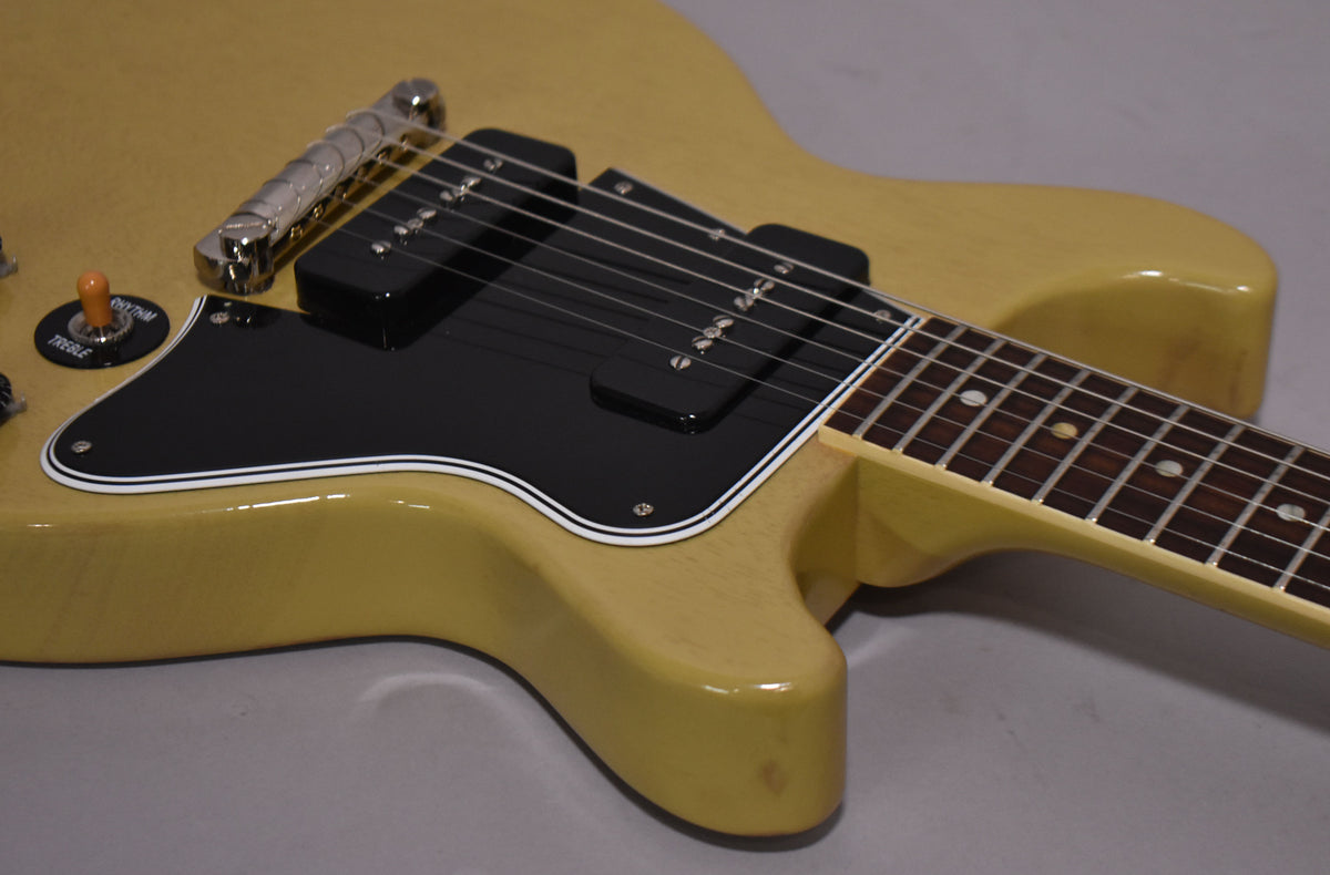The TV yellow double-cut guitar body, with a black pickguard and two black P90 pickups, is angled from the lower bout.