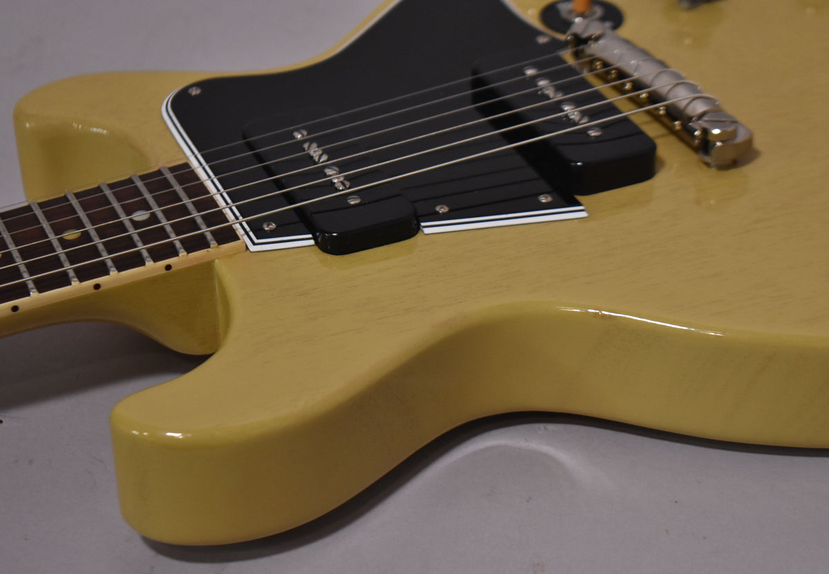 Close-up of the TV yellow double-cut body and neck joint, showing the black pickguard, two P90 pickups, and tune-o-matic bridge.